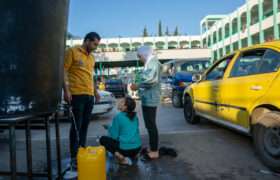 Mohammed and his two daughters are filling their containers with drinking water inside a government school in Deir al-Balah, a facility used as a shelter by Palestinians who have fled from the northern Gaza Strip.