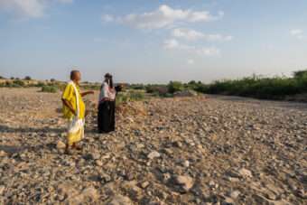 a 50-year-old farmer, and the Farmer and Field Facilitator Raed Ali Al-Awd, stand on the dry land in Al-Khaddad area in Yemen.