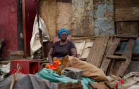 Woman sitting outside demolised house in Kenya post flash floods