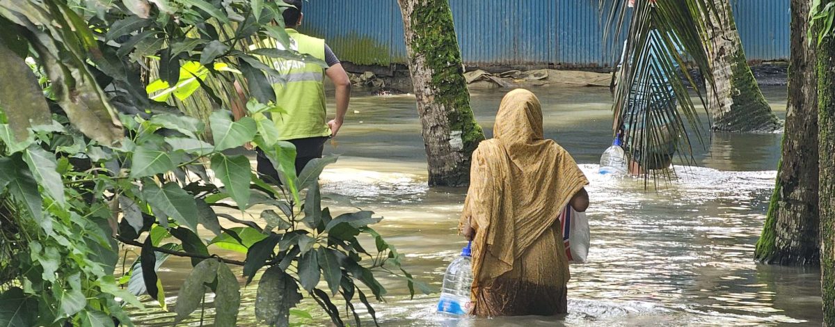 Woman walking in flood with supplies of clean water and dry food